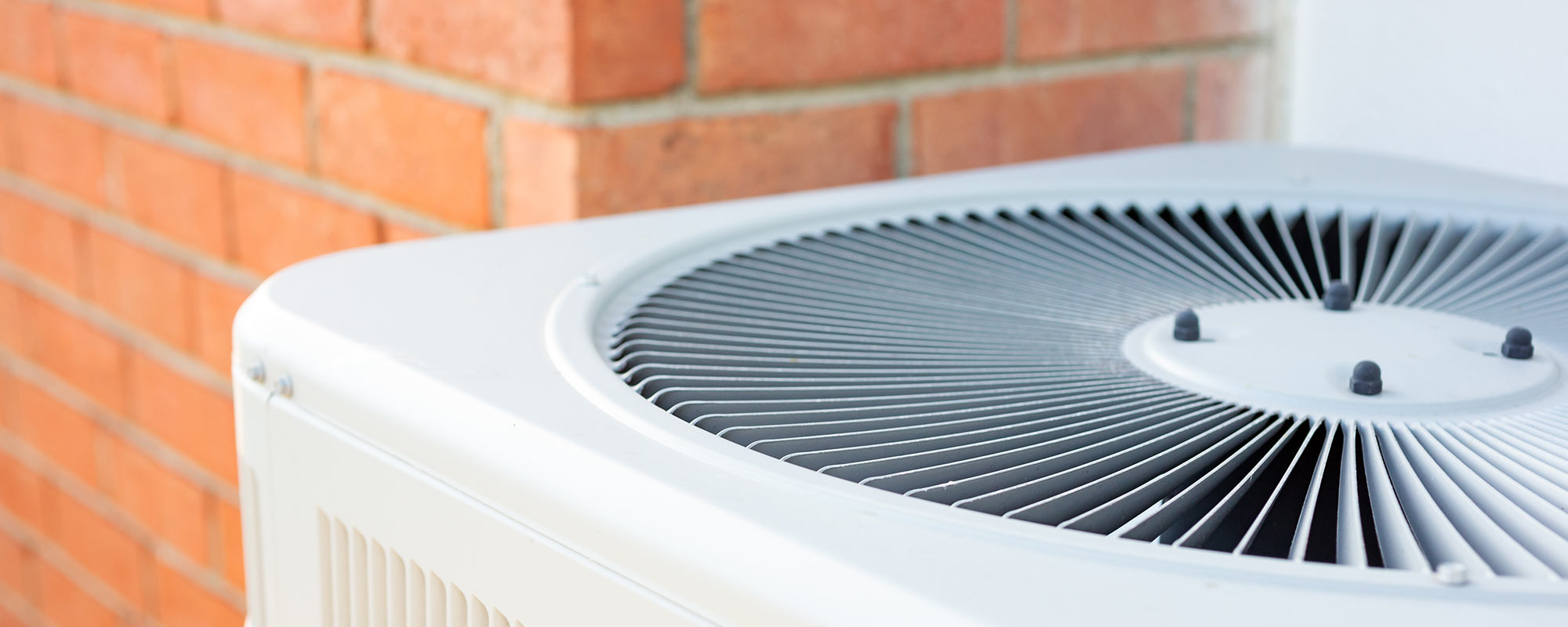 closeup of heat pump outside of brick house