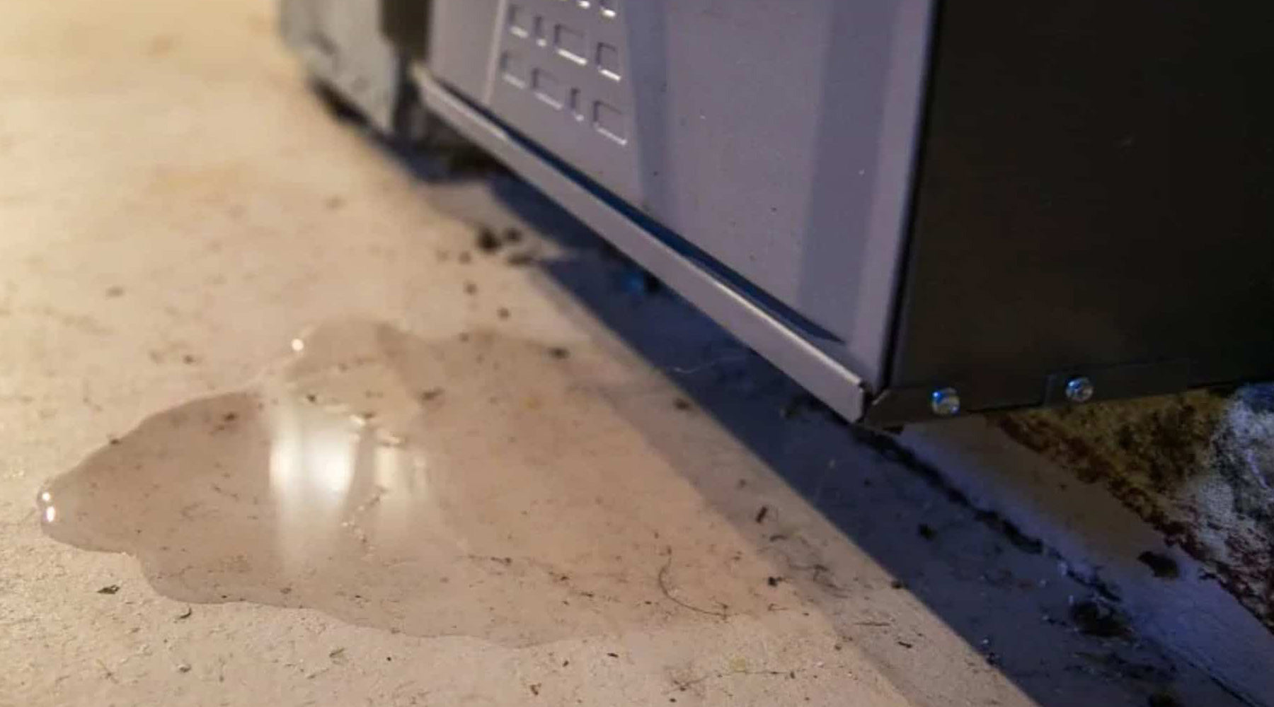 puddle of water leaking from underneath air conditioner unit inside house