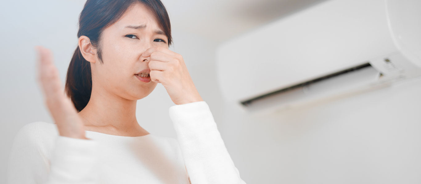 woman holding nose because of burning smell from AC