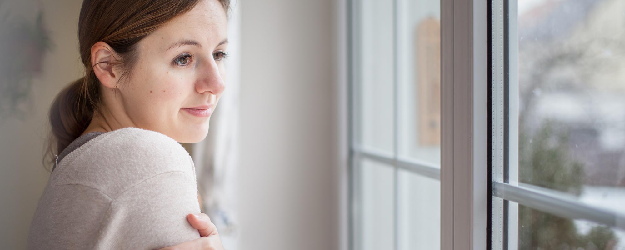 woman staring out of window wondering how long does a furnace last