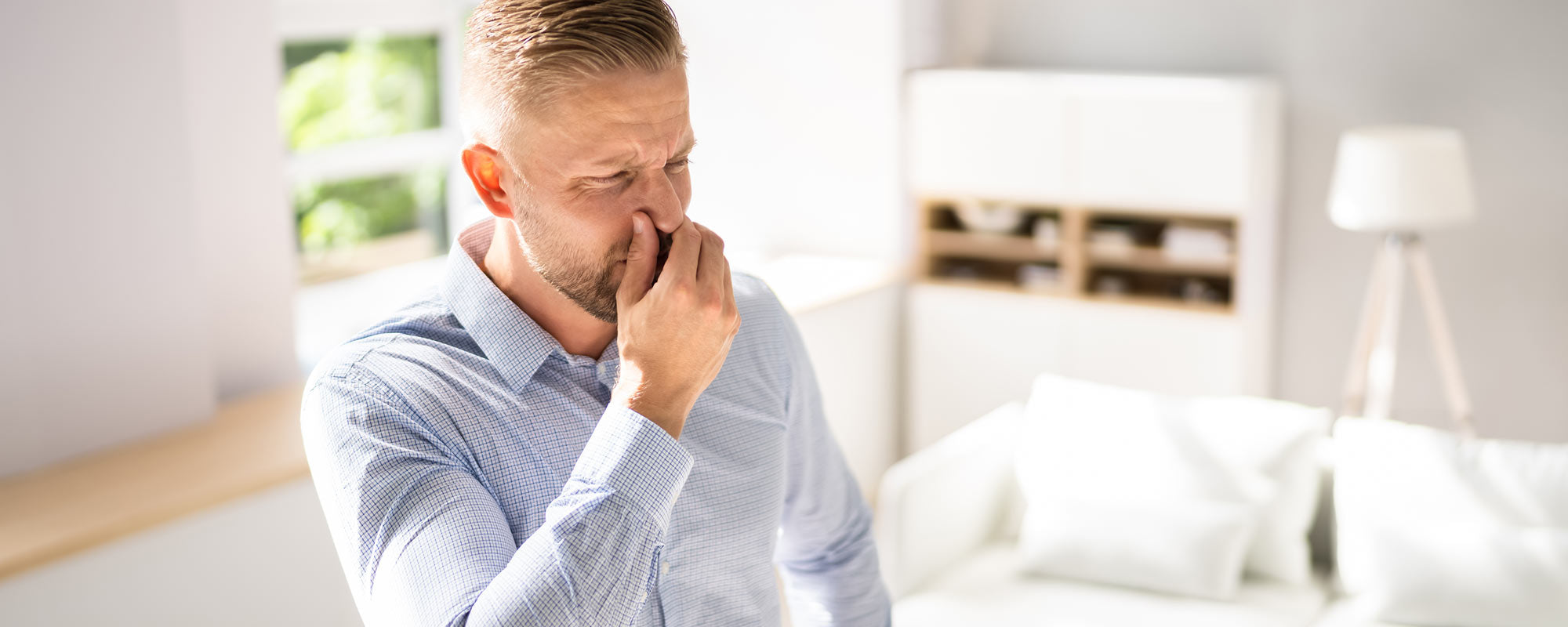 man holding nose burning smell in house