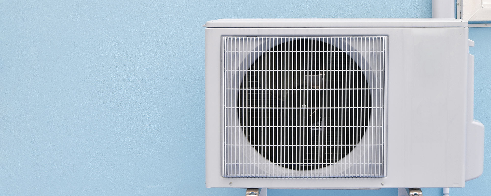 ductless mini split heat pump installed outside of house with blue exterior blue wall