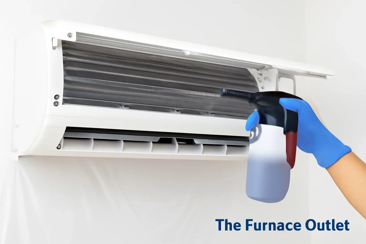 A mini-split AC unit being cleaned, showing its evaporator coils and a hand spraying cleaning solution.