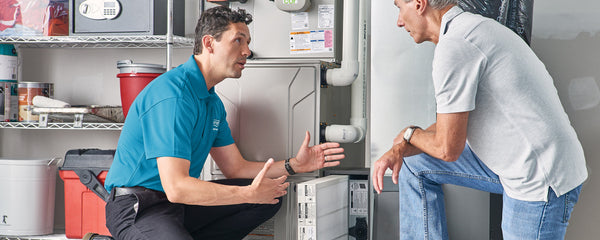 HVAC professional explaining the importance of filter on central heating system to older man