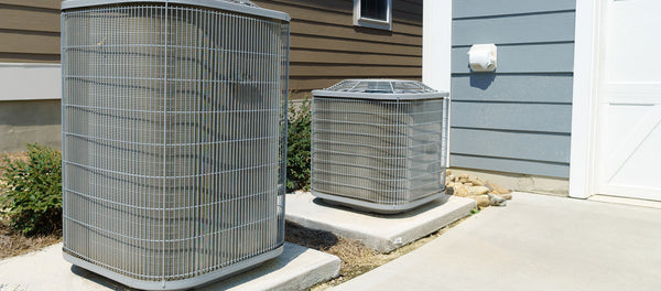 central air conditioner units outside of home with blue siding and white garage door