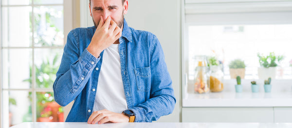 man holding his nose because of fishy smell from air conditioner
