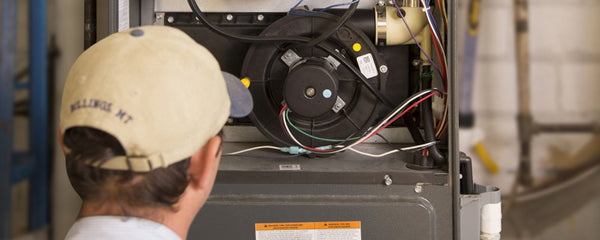 man wearing baseball hat performing furnace maintenance