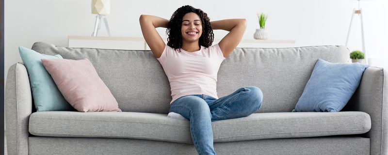  woman sitting on couch enjoying air flow from furnace.